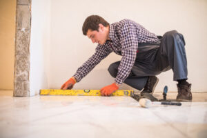 home-tile-improvement-handyman-with-level-laying-down-tile-floor